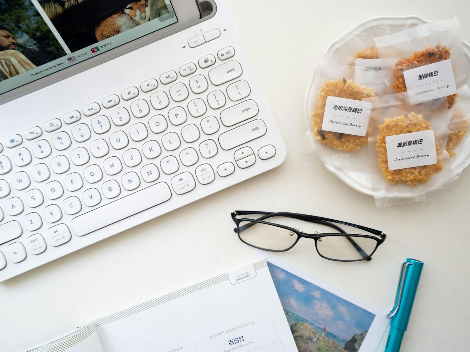 Laptop and snacks near eyeglasses on white surface